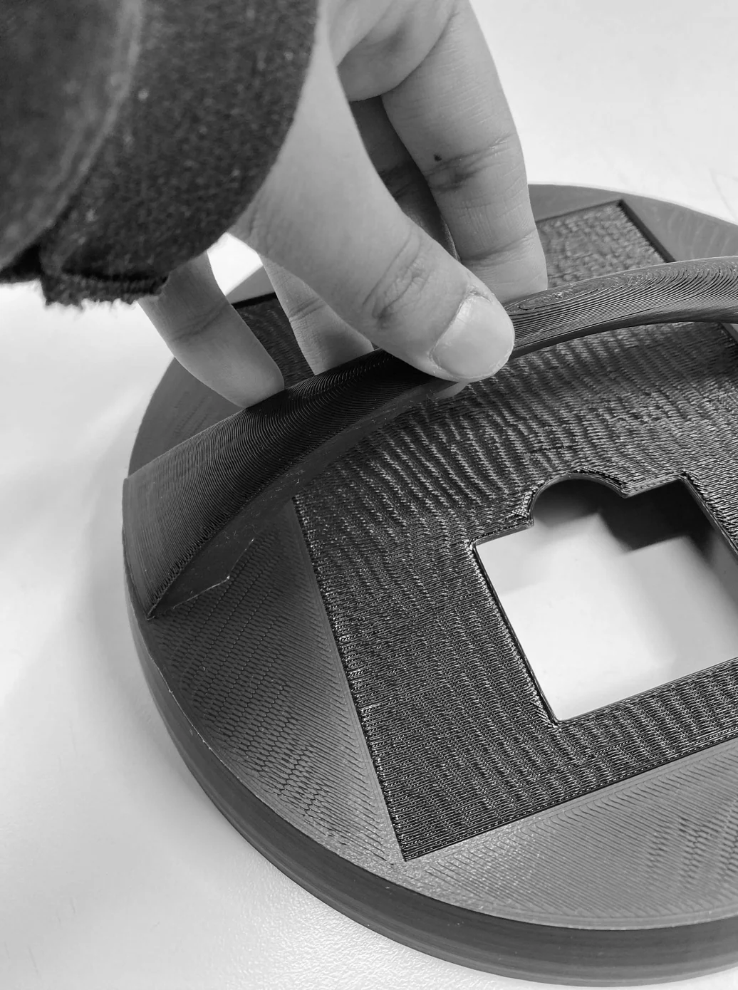 Hand attaching fabric to the 3D-printed top disc — securing the woven shade to the mechanism housing