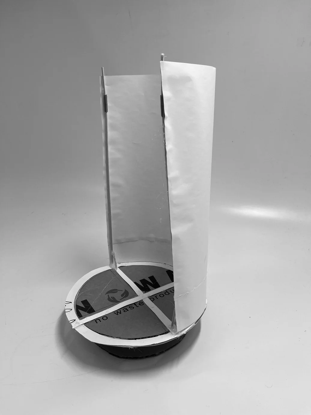 Early paper prototype — tall cylindrical form study on a circular cardboard base