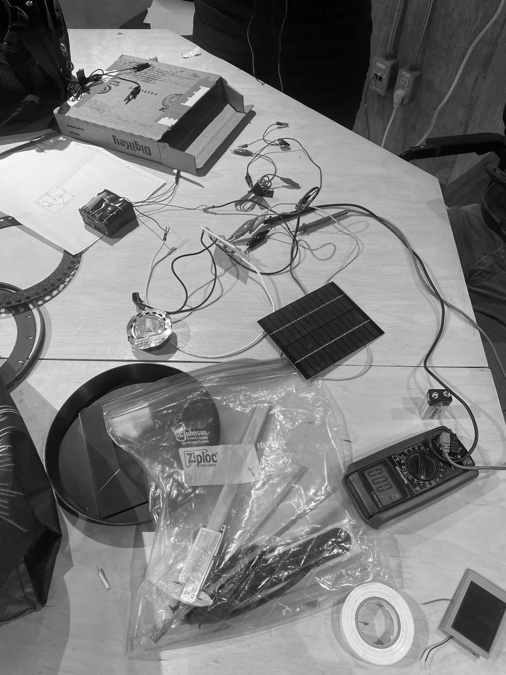 Electronics components, bags and multimeter laid out on a table