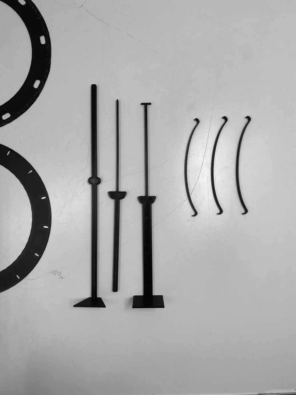 All structural parts laid flat — ring disc, extrusion rods, and spring steel strips