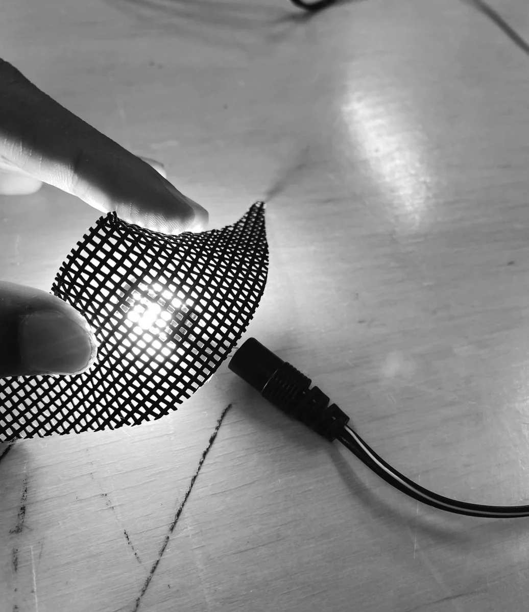 Fabric mesh stretched over a wire frame, unlit — testing structure and drape