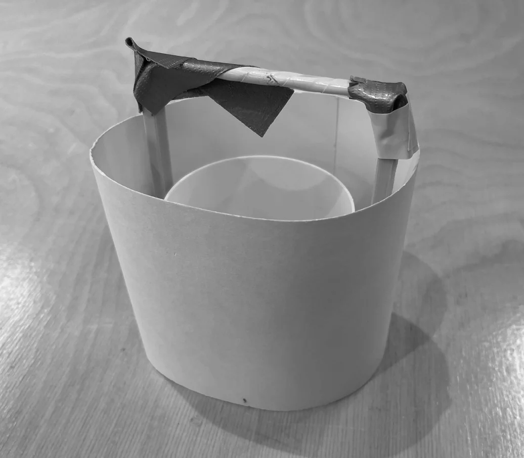 Paper prototype testing carry-mode proportions — cylindrical body with handle arching overhead