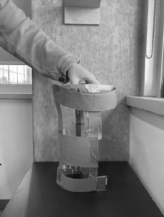 Early cardboard form study — cylinder proportions with top module lifted by hand