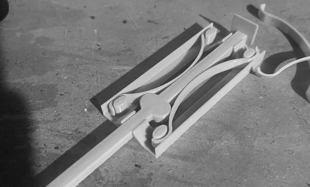 Multiple 3D-printed mechanism iterations laid out — different geometries for the spring-steel handle seat