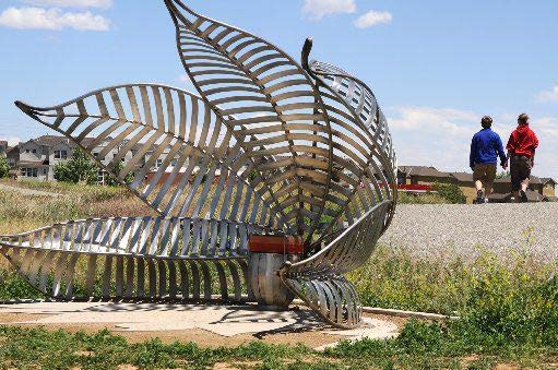 Large metal leaf-shaped sculptural structure in an open field