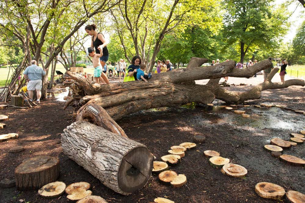 Children climbing on large logs in a nature play area
