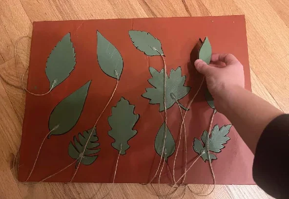 Leaf silhouette cutouts on a terracotta panel — early lift-to-reveal panel prototype