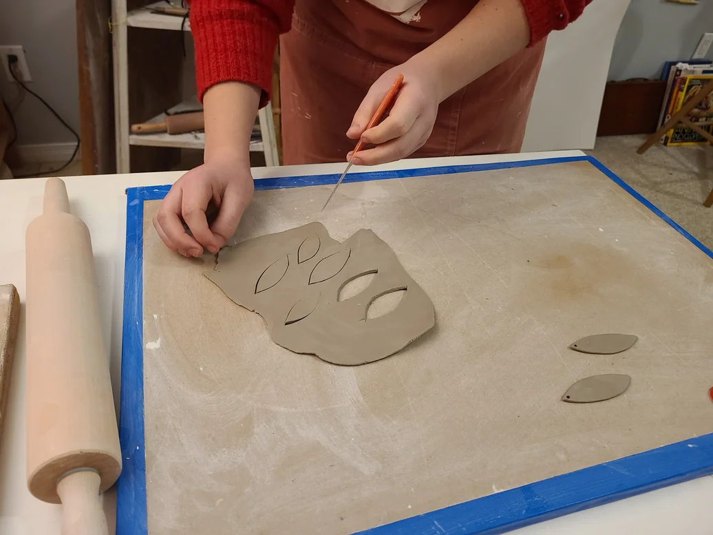 Carving pinecone-inspired shapes out of rolled clay